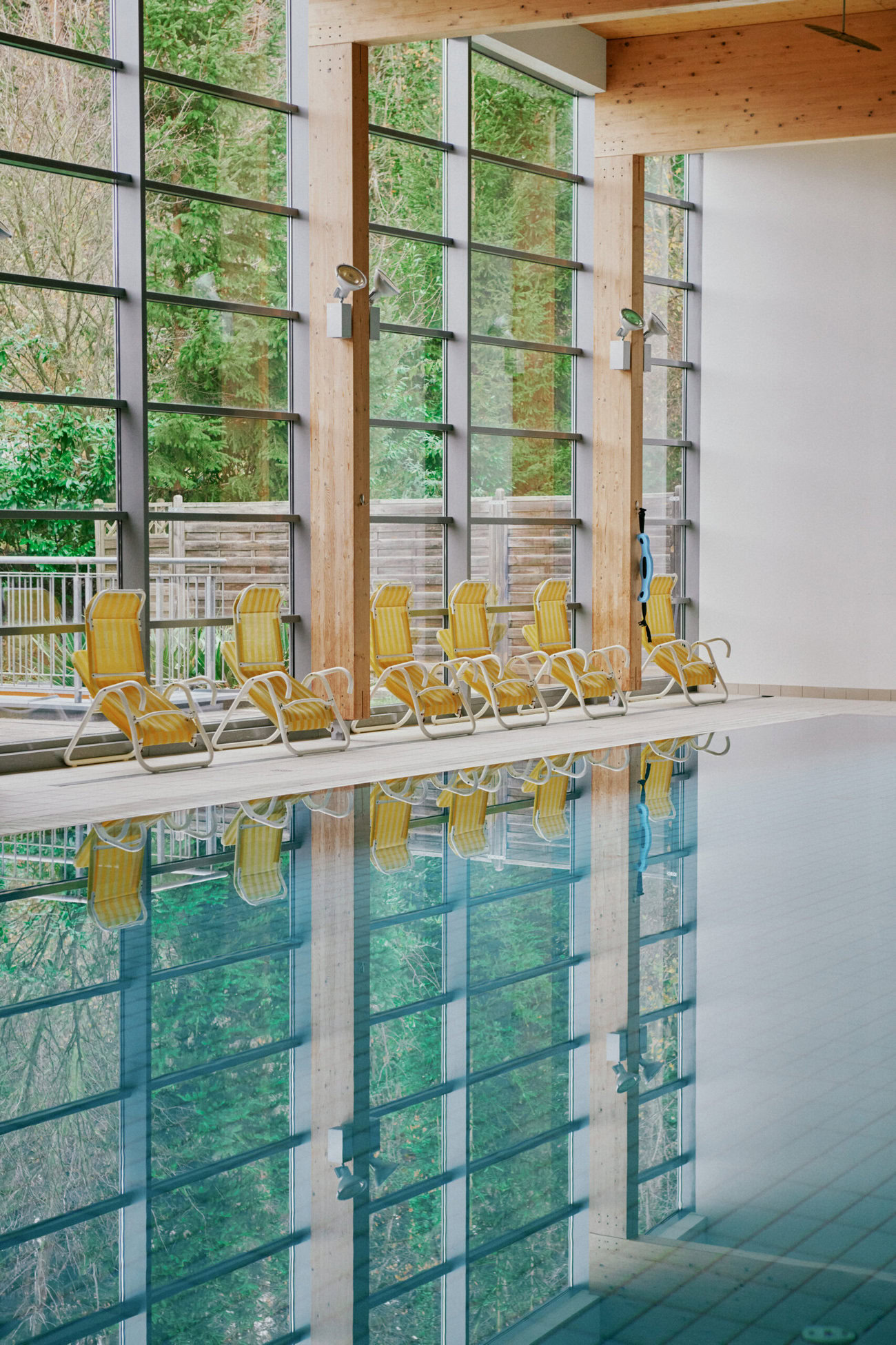 Man sieht den Indoor-Pool des Gesundheitszentrum Bad Sauerbrunn. Neben dem Pool stehen zahlreiche Liegen und eine Große Glas-Front ermöglicht einen schönen Blick nach draußen.