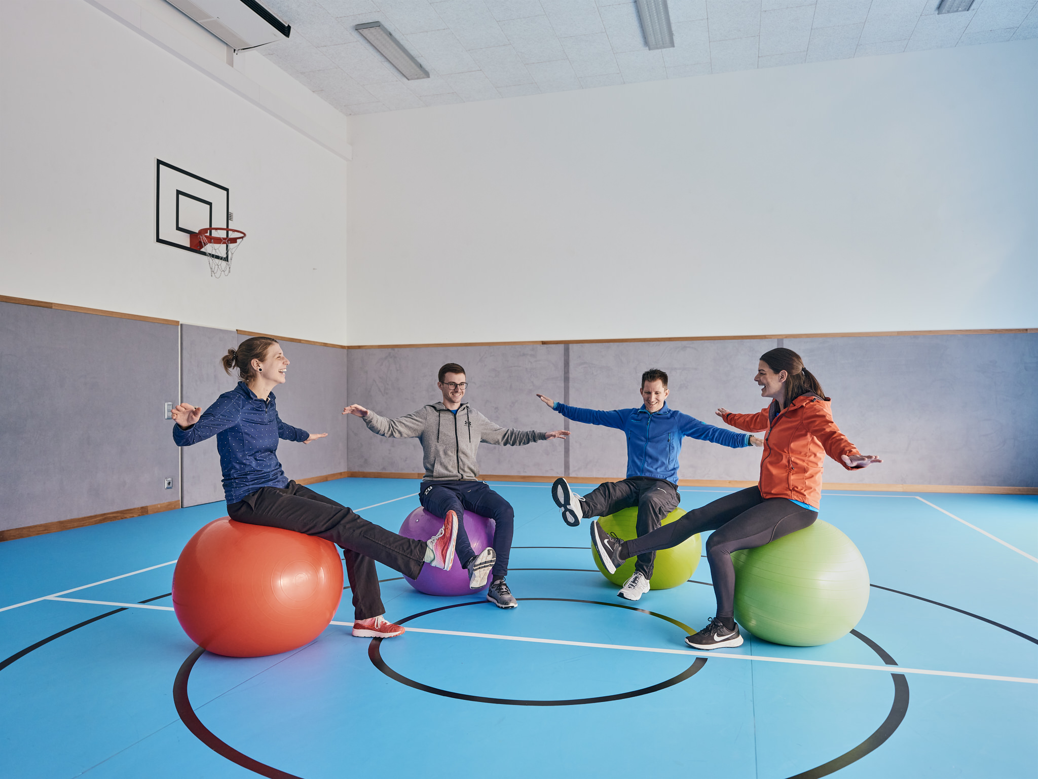 Vier Personen machen Übungen auf großen Gymnastikbällen